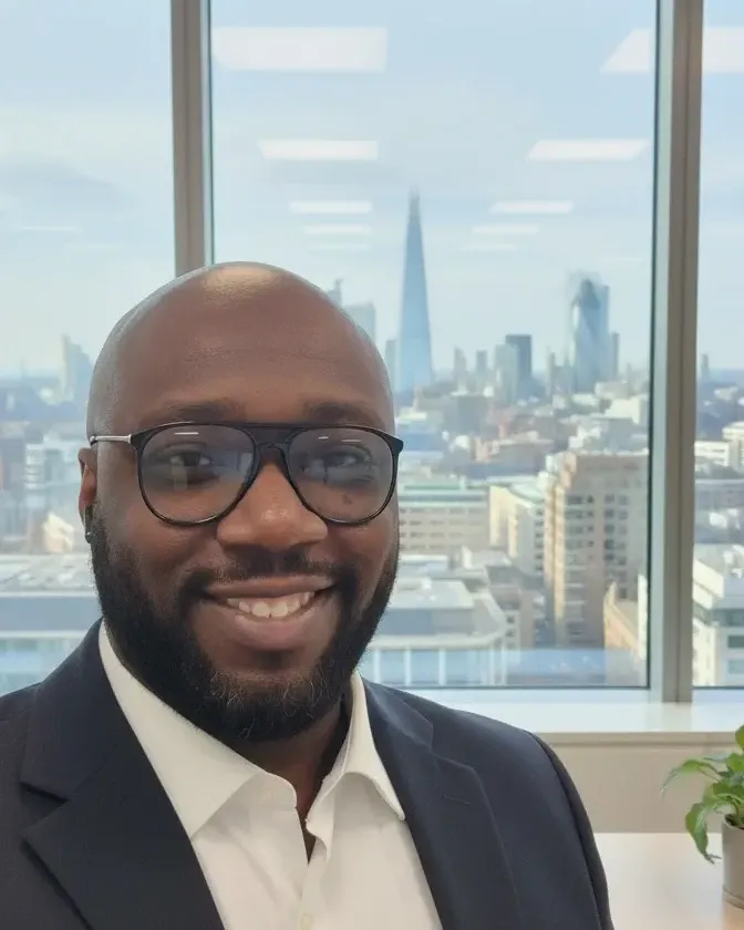 S. Teniola Ajayi in an office, with the London skyline behind him